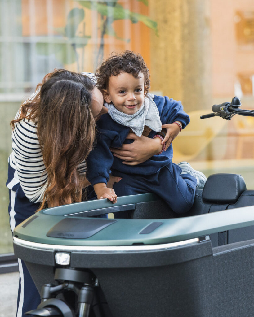 Parent lifting a smiling child into the Lovens Explorer 2 cargo bike